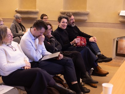 People sitting front row at a conference, one looks at the camera smiling