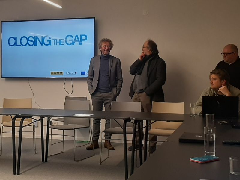 A group of men in front of a screen displaying the words "Closing the Gap"