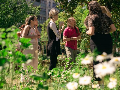 A group of people in a park, springtime, windy, one is holding a bee hive