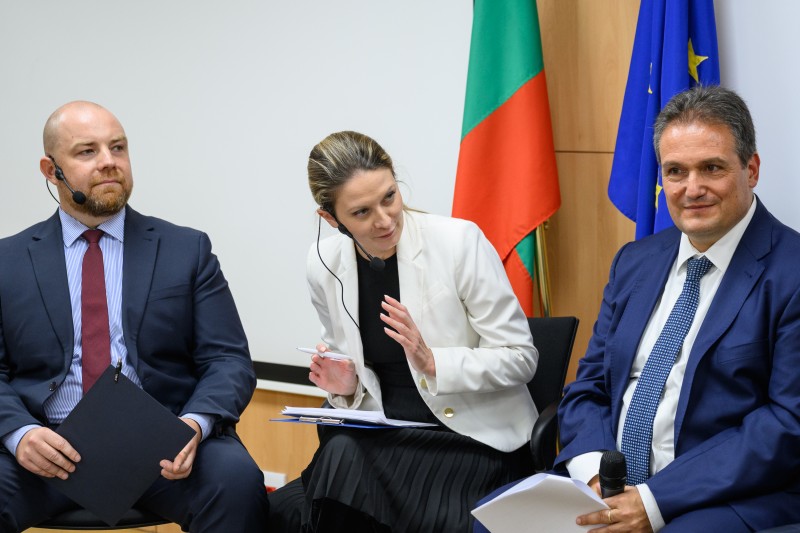 Three people speaking at a panel discussion, formal