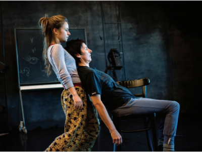 two people dancing against a dark background