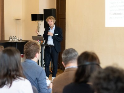 A man giving a speech to a small audience, formal