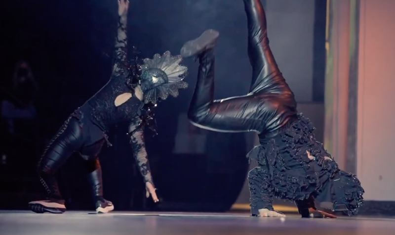 two people performing on a stage, wearing black costumes