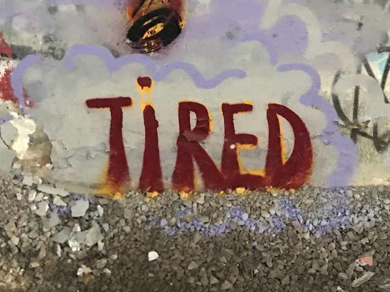 The word "tired" written on a wall