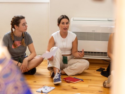 Two youngsters sitting on the floor and discussing during a workshop