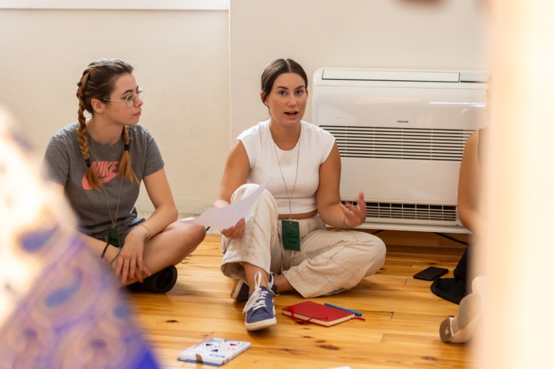 Two youngsters sitting on the floor and discussing during a workshop