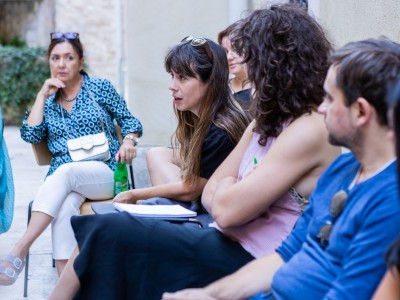 A group of young people at an outdoors roundtable, exchaging ideas