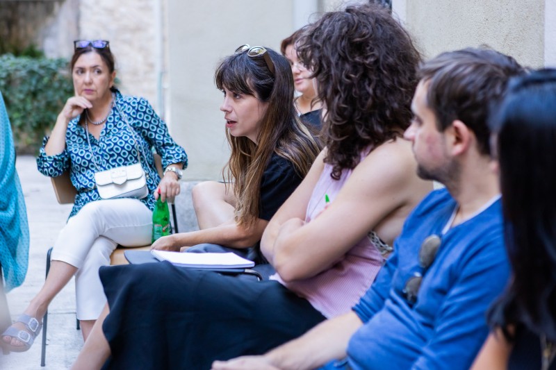 A group of young people at an outdoors roundtable, exchaging ideas