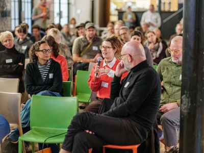 A woman speaking at a conference from the audience